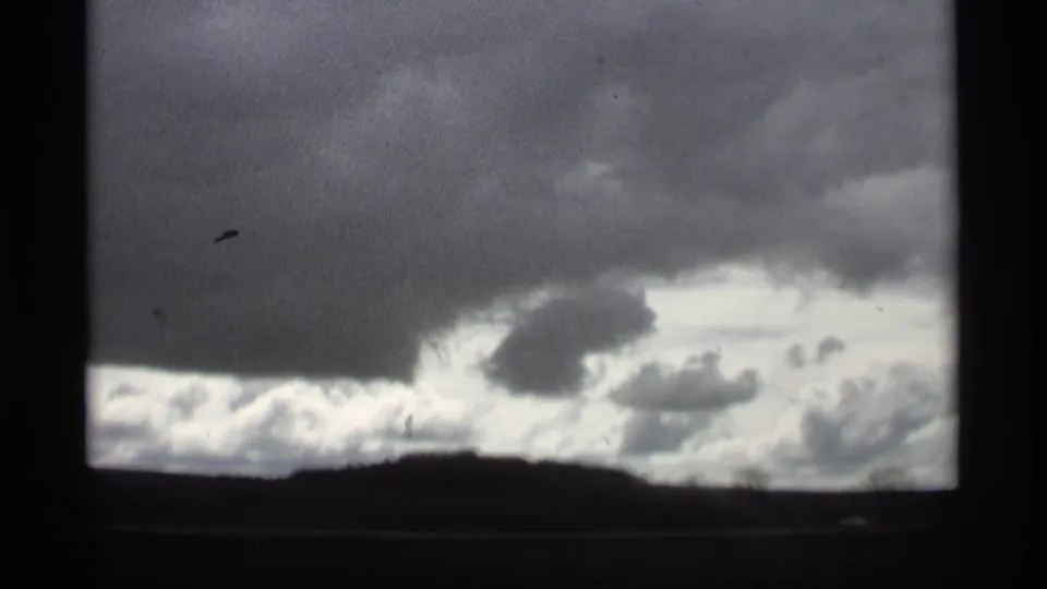 1969 Holland, Michigan home-movie frame of stormy clouds above a dark, low landscape.