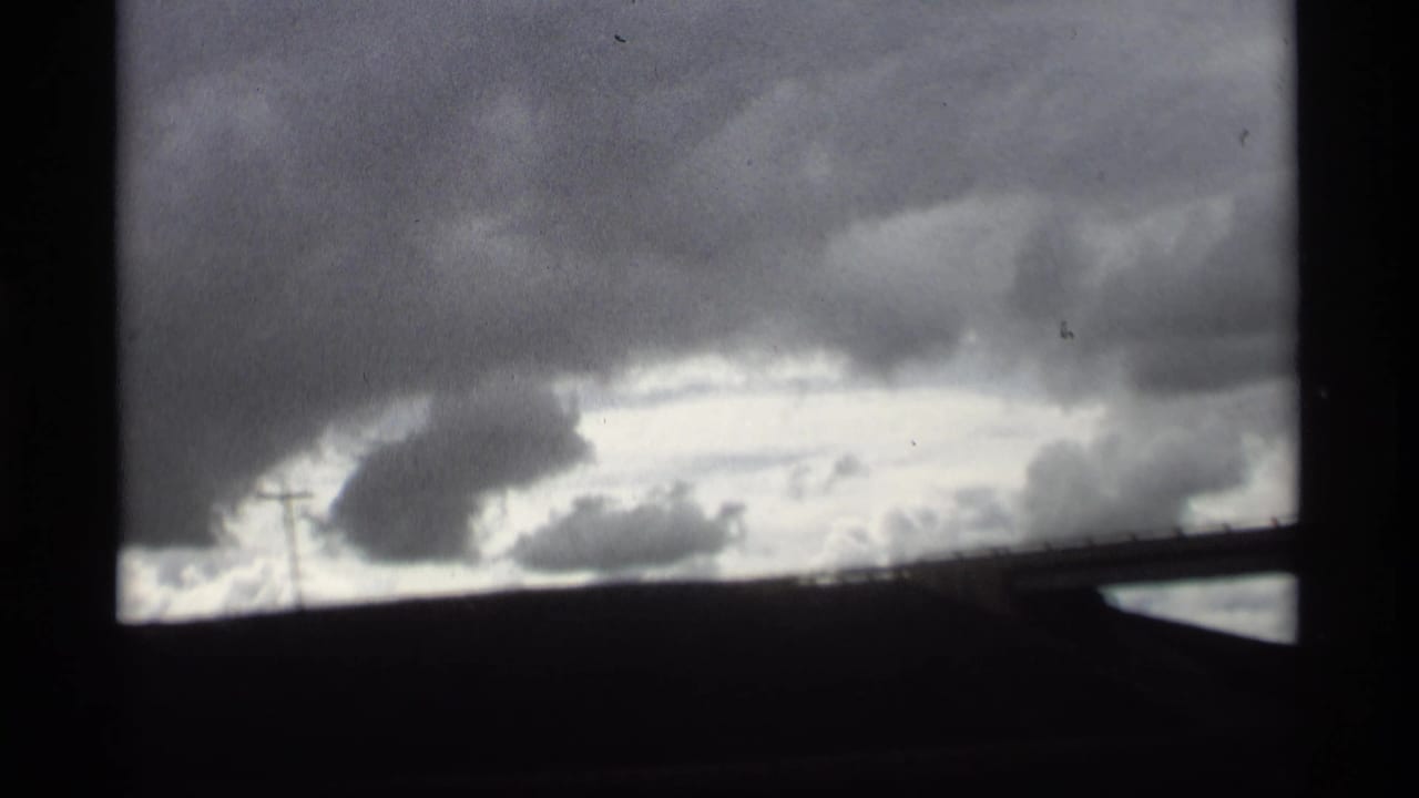 Overcast sky and low dark horizon with a diagonal bridge or window edge.