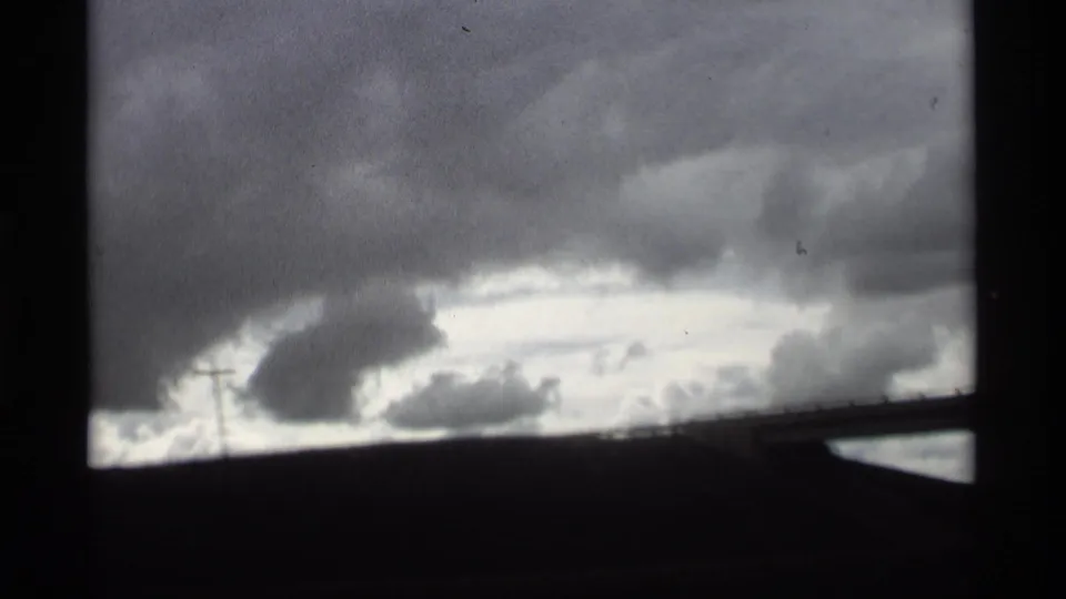 Overcast 8mm travel view in Holland, Michigan, with gray cloud banks, a dark horizon, and diagonal foreground structure.