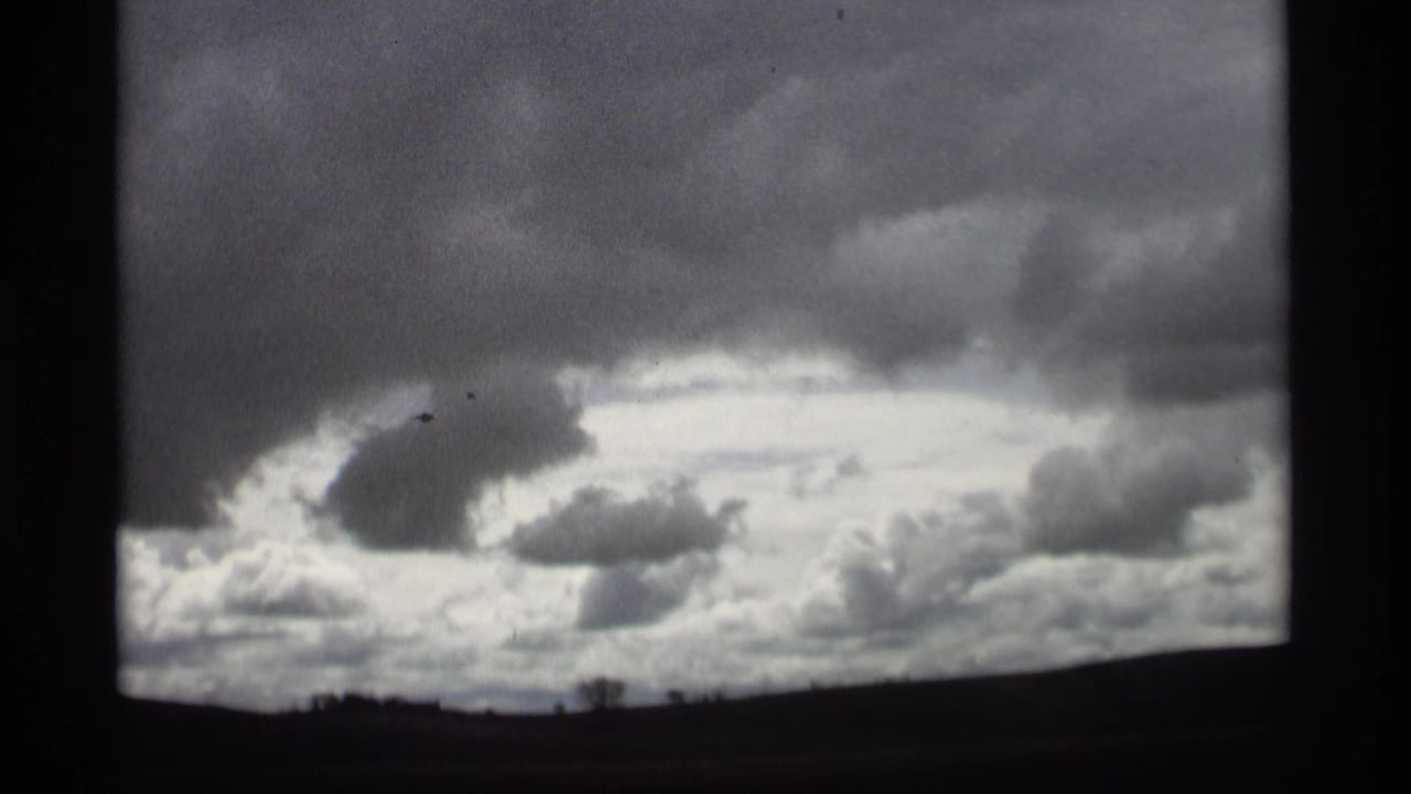 Dark overcast sky above a low horizon, framed by black film borders.