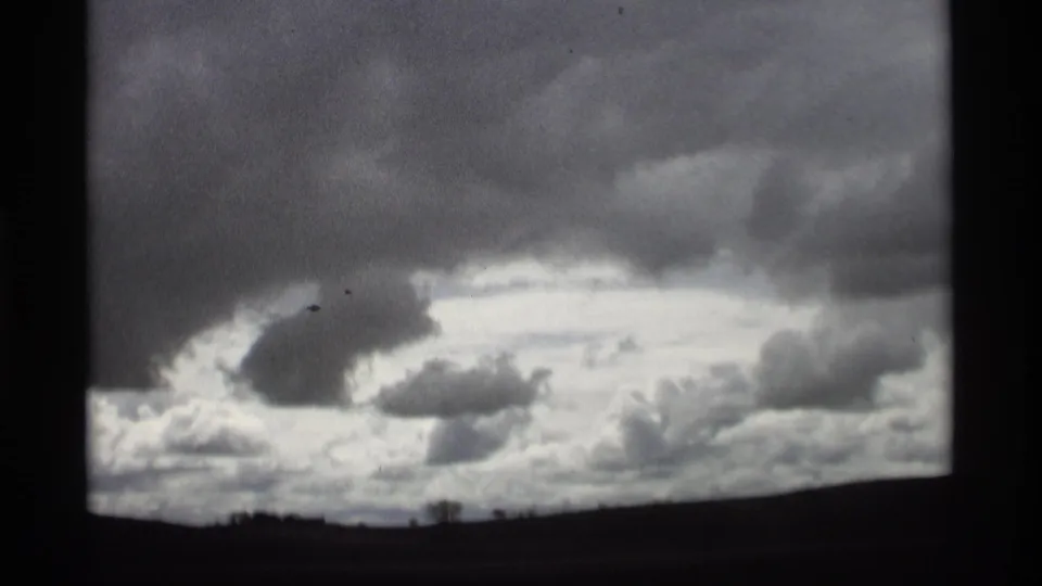 1969 8mm frame from Holland, Michigan showing a dramatic cloudy sky over a low roadside horizon.