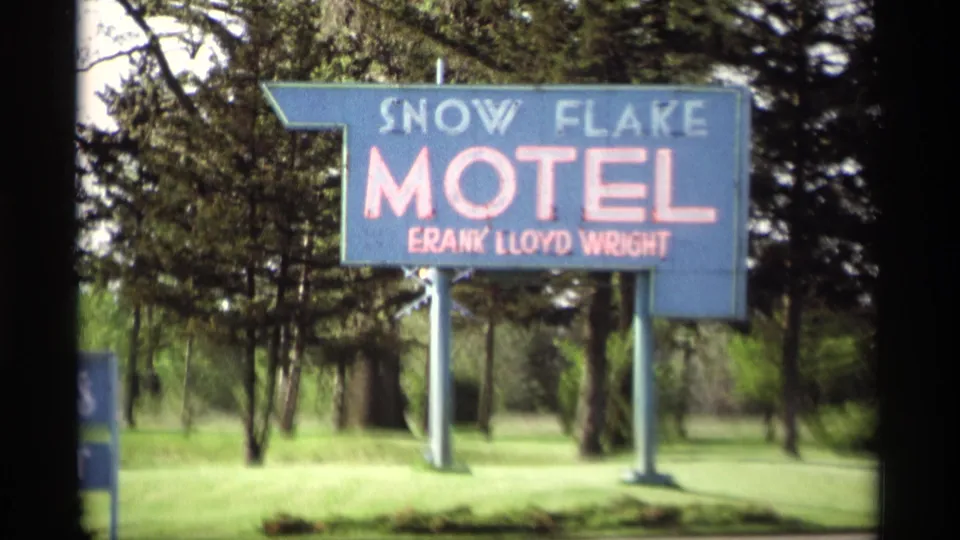 1969 Holland, Michigan home-movie frame of the blue Snow Flake Motel sign with red lettering against trees and lawn.