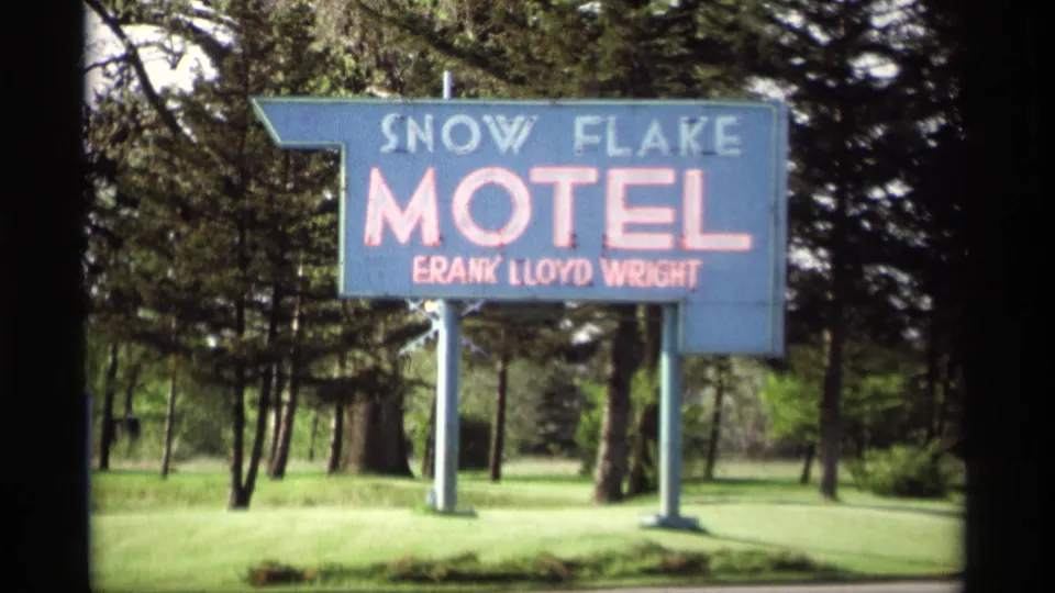 Clear 1969 Holland, Michigan view of the Snow Flake Motel roadside sign, including red lettering and wooded background.