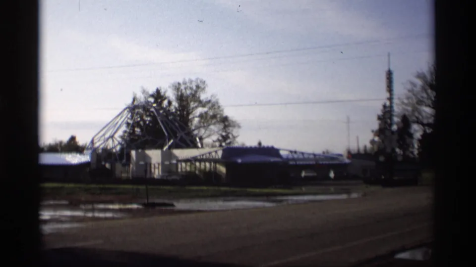 Holland, Michigan roadside scene with wet pavement, overhead wires, low buildings, and a geometric motel roof structure in the distance.