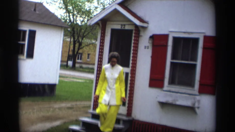 The woman begins stepping down from the porch in the 1969 Holland, Michigan home-movie scene.