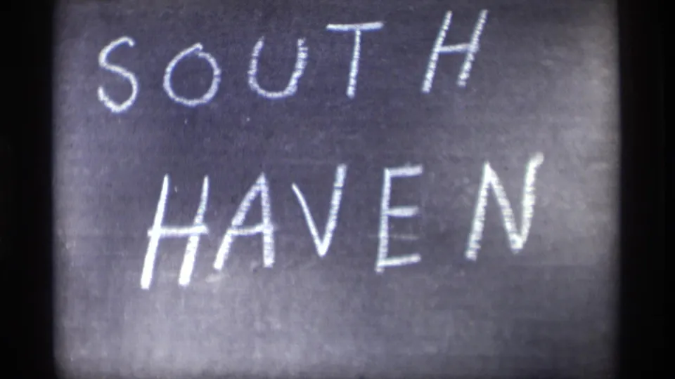 Final close-up frame of the hand-lettered SOUTH HAVEN chalkboard, with soft 8mm focus and dark frame edges.