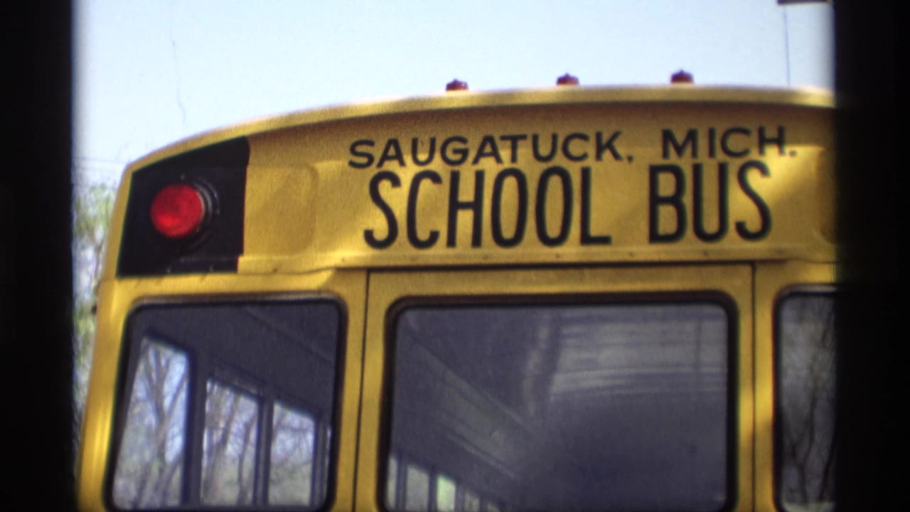 Rear of a yellow Saugatuck school bus with red taillight and large windows.