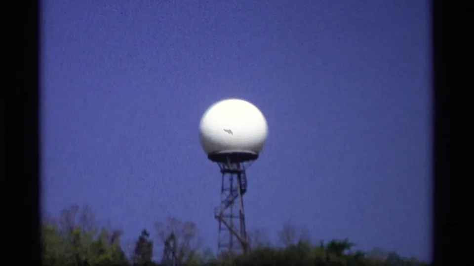 1969 Holland, Michigan frame with the radar dome centered high above a wooded line, photographed in soft 8mm home-movie focus.