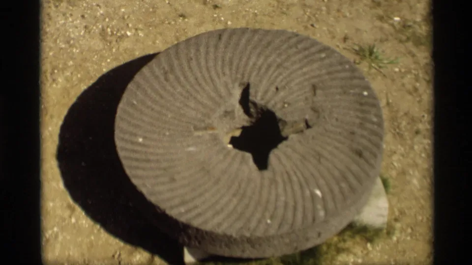 Close 8mm frame from the same Holland, Michigan clip showing a round ridged object on sandy ground, separate from the flag and windmill views.