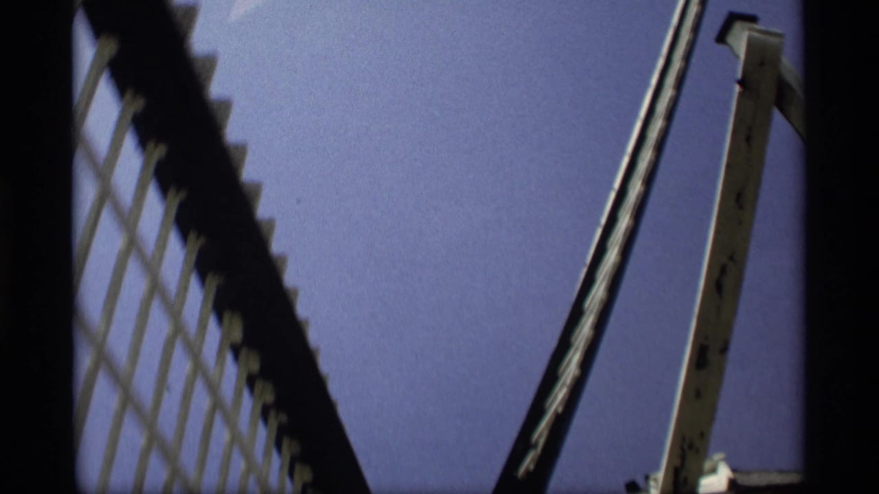 1969 Holland, Michigan 8mm frame showing a low-angle view of large windmill blades and a pale wooden support against blue sky.