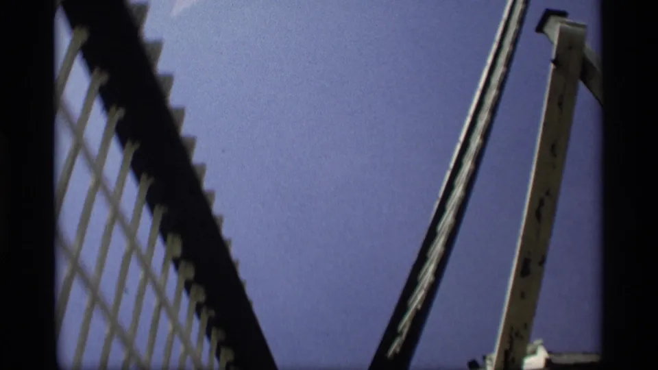 1969 Holland, Michigan 8mm frame showing a low-angle view of large windmill blades and a pale wooden support against blue sky.