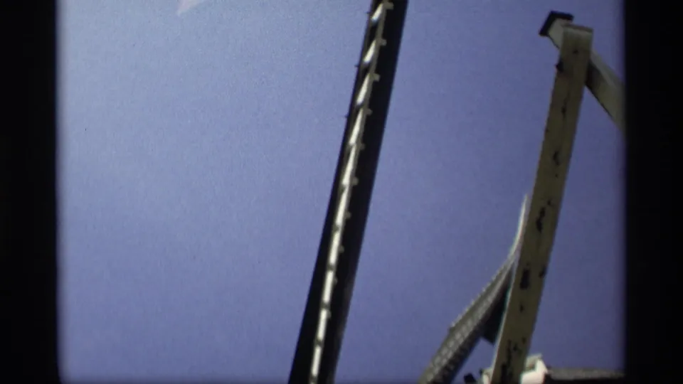 Low-angle 1969 Holland, Michigan frame with dark windmill blades and a tall wooden support filling the sky.