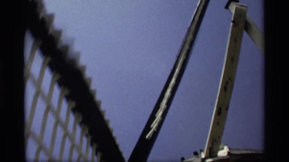 1969 8mm frame from Holland, Michigan showing a soft low-angle view of windmill latticework, blade edge, and wooden support.
