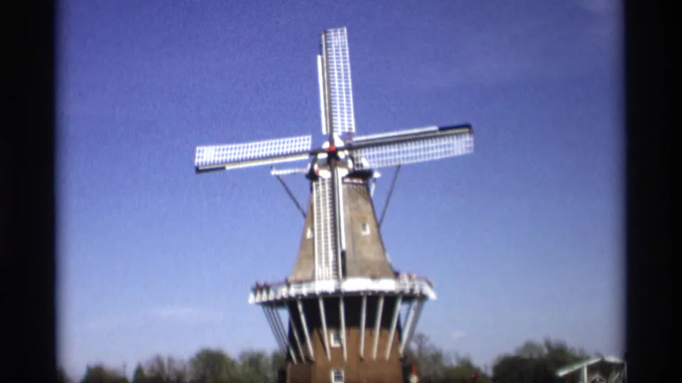 1969 Holland, Michigan 8mm view of a Dutch-style windmill with white sails under a clear blue sky.