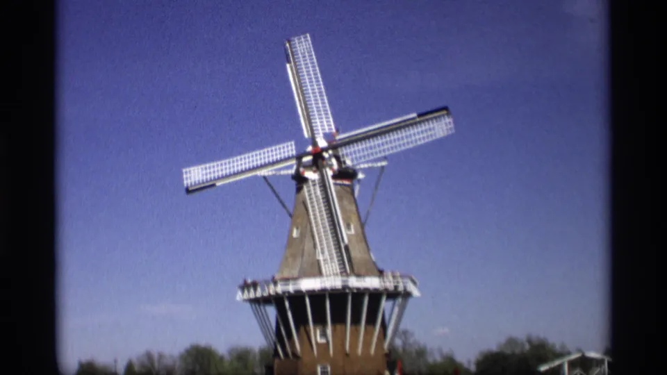 1969 8mm view of a Dutch-style windmill in Holland, Michigan, framed from below against a clear blue sky.