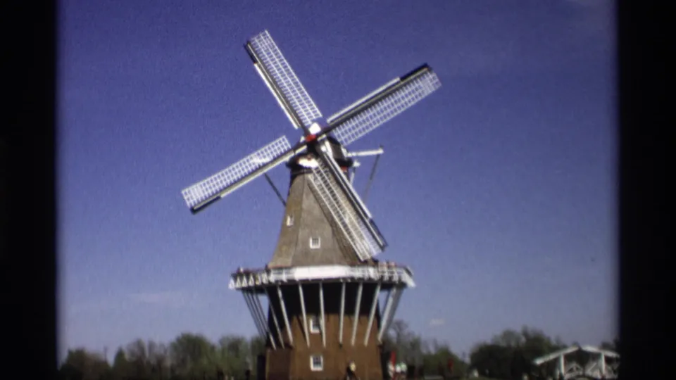 Dutch-style windmill in Holland, Michigan, shown from a visitor viewpoint with small distant people near the base.