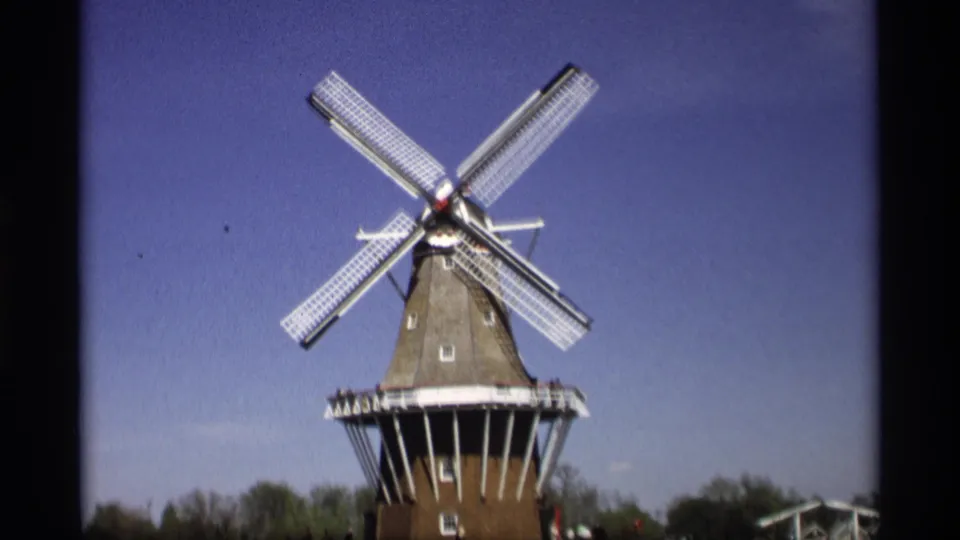 Centered 1969 home-movie frame of the Holland, Michigan windmill, with white sails and gallery railing visible.