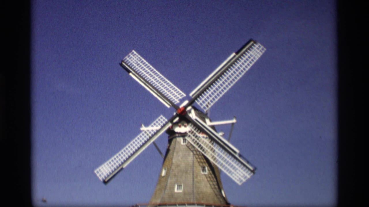 Dutch-style windmill with four white lattice blades against a clear blue sky.