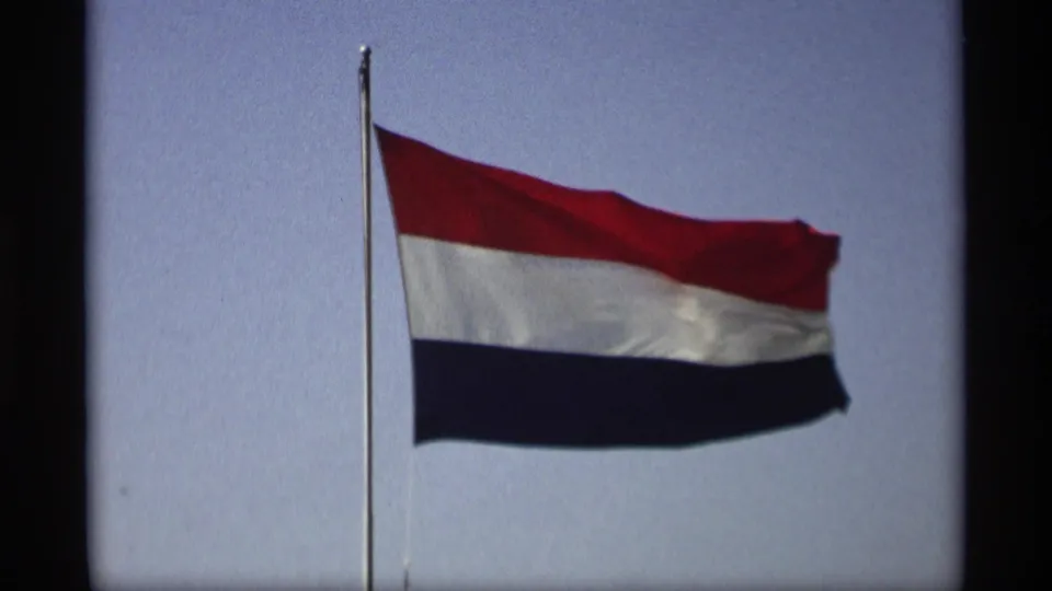 Netherlands flag waving against a blue sky in supplied 1969 Holland, Michigan 8mm home-movie footage.