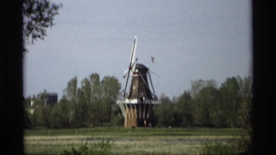 1969 Holland, Michigan frame showing a Dutch-style windmill beyond a grassy field, with trees and pale sky behind.