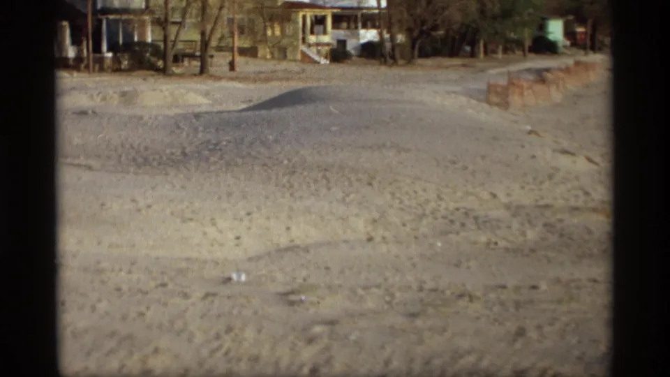 The home-movie view holds on a sandy neighborhood street with houses and leafless trees in Holland, Michigan.