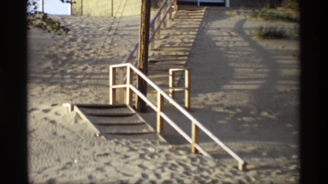 Sandy beach staircase with white railings, a utility pole, and dune paths.