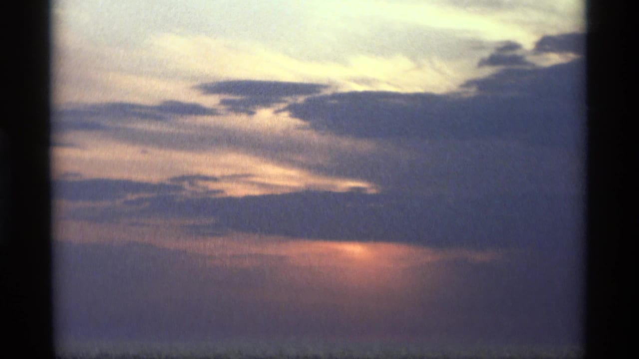Blue cloud bands and orange sunset light above a dark water horizon.