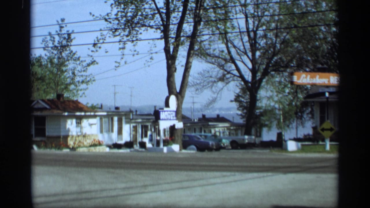 1969 Holland, Michigan roadside view with a motel sign, lodging buildings, parked cars, trees, and a Lakeshore Resort sign.