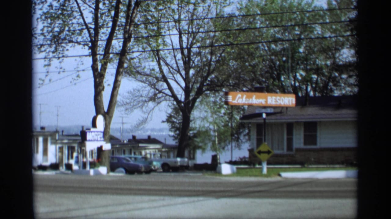 Motel and Lakeshore Resort signs beside low lodging buildings and parked cars.