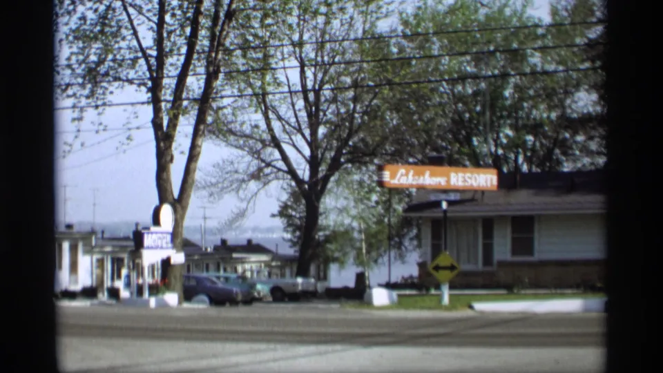 1969 Holland, Michigan motel and resort frontage with parked cars, leafy trees, power lines, and a quiet street.
