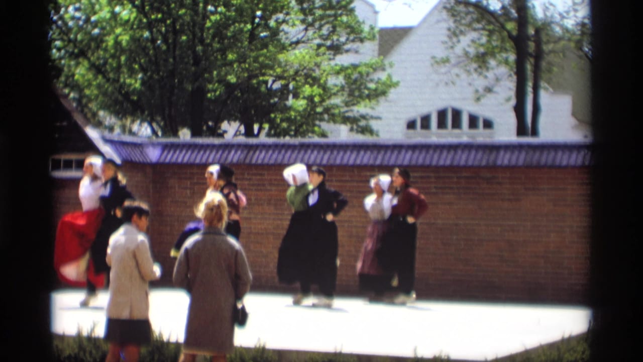 In Holland, Michigan in 1969, costumed women in white bonnets and long skirts perform a folk dance before spectators outdoors.