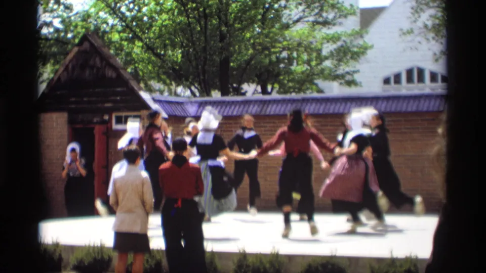 The 1969 Holland, Michigan footage shows folk dancers forming a circle near a brick wall as spectators observe from the foreground.
