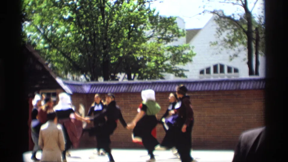 Final frame of the 1969 Holland, Michigan dance scene, showing women in Dutch-style costumes circling on a bright outdoor stage.