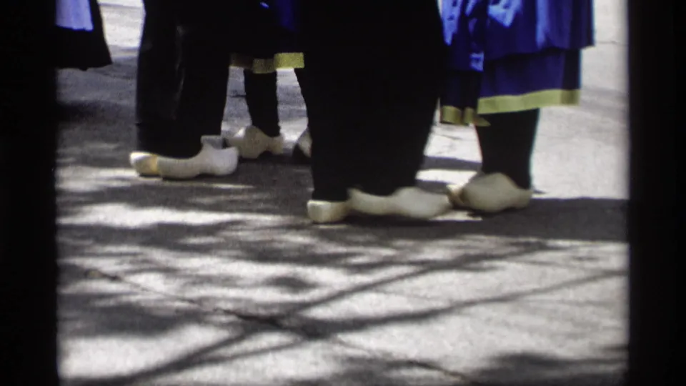 Close-up from the 1969 parade emphasizes white clogs, dark stockings, and blue skirts as costumed marchers pass the camera.