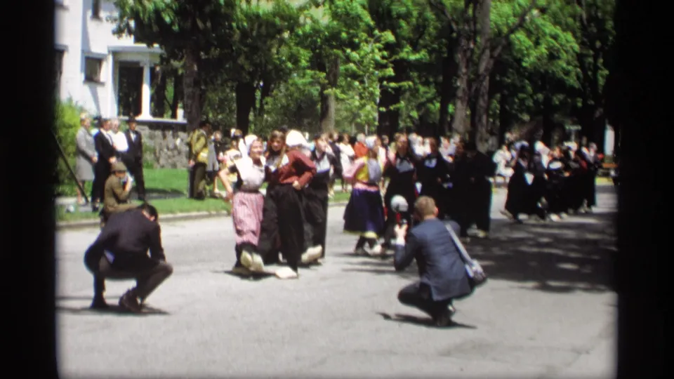 1969 Holland, Michigan street scene with Dutch folk dancers, spectators, and two foreground photographers documenting the performance.