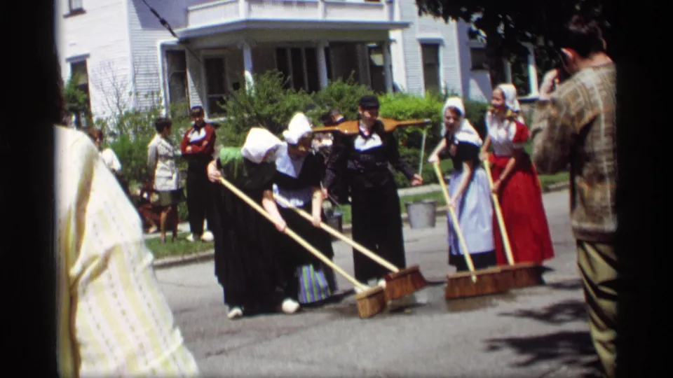 Costumed women in white bonnets appear to sweep the street during a Dutch-style public performance in Holland, Michigan.