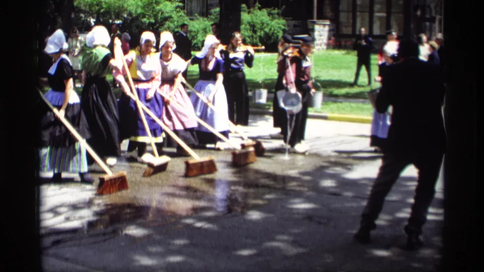 The 1969 Holland, Michigan footage shows women in Dutch-style costumes sweeping wet pavement as spectators and houses appear nearby.