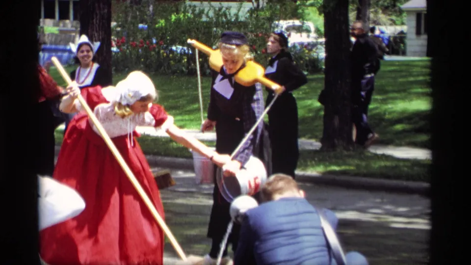 Women in Dutch-style dress demonstrate poles, a wooden yoke, and metal buckets for spectators at a 1969 outdoor festival in Holland, Michigan.