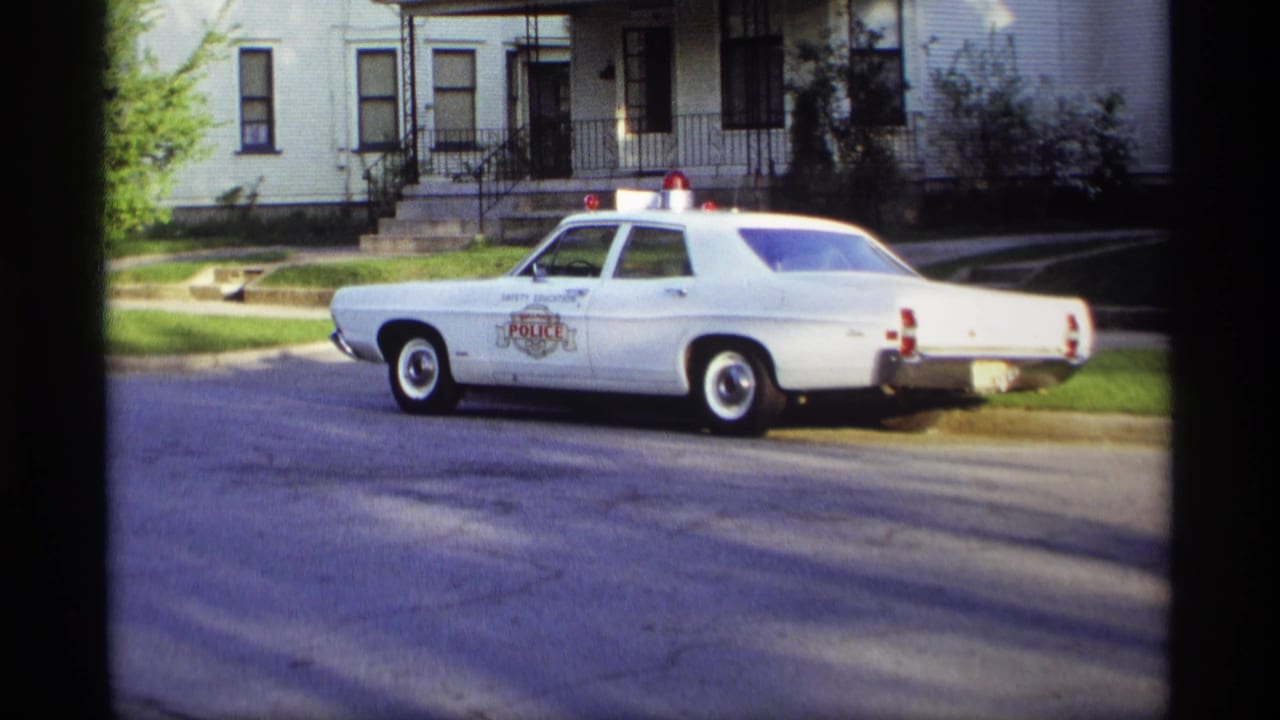 White police sedan parked along a residential street near houses.