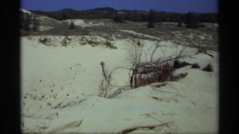 Holland, Michigan dune terrain with sparse vegetation and a small weathered wooden structure visible in the sand.