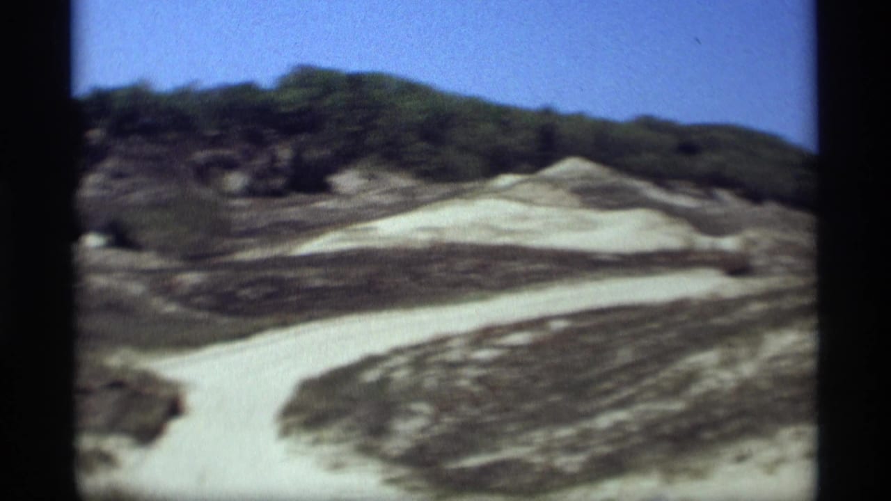 1969 Holland, Michigan home-movie view of a winding snow track across wooded hills beneath a clear blue sky.
