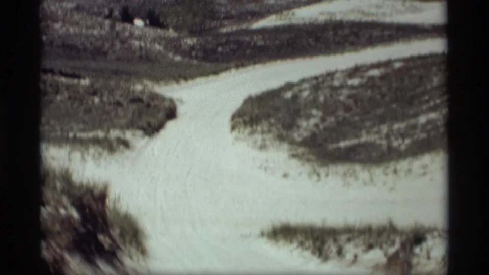 A vintage 8mm winter view shows a snow-covered path curving through wooded terrain in Holland, Michigan.