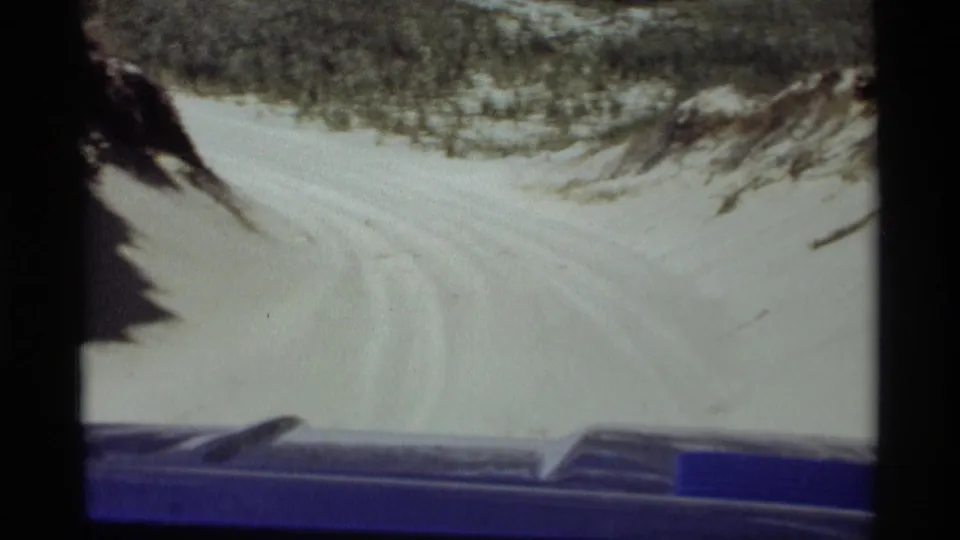 1969 Holland, Michigan home-movie view from inside a vehicle on a sandy dune trail with tire tracks and sparse vegetation.