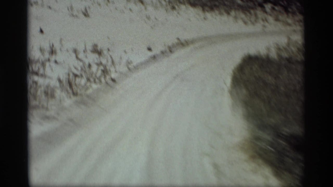 8mm home-movie frame from Holland, Michigan showing the dirt road curving ahead through a rural roadside landscape.