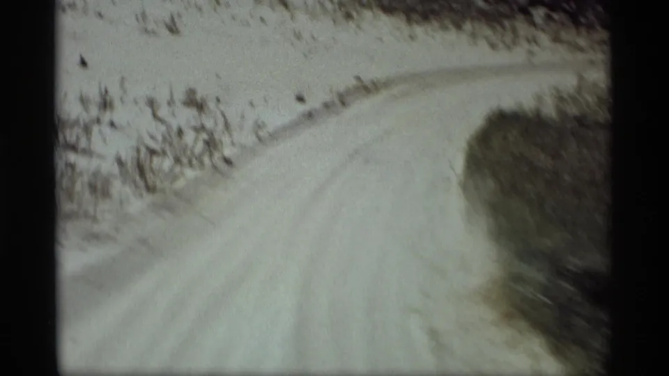 8mm home-movie frame from Holland, Michigan showing the dirt road curving ahead through a rural roadside landscape.