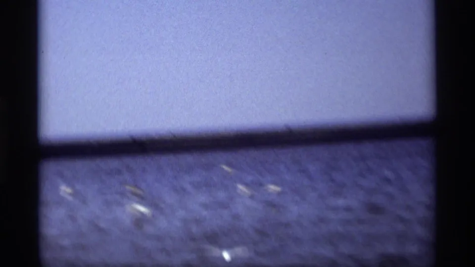 The final 1969 8mm frame looks across calm water near Holland, Michigan, with small distant boats and a soft blue sky.
