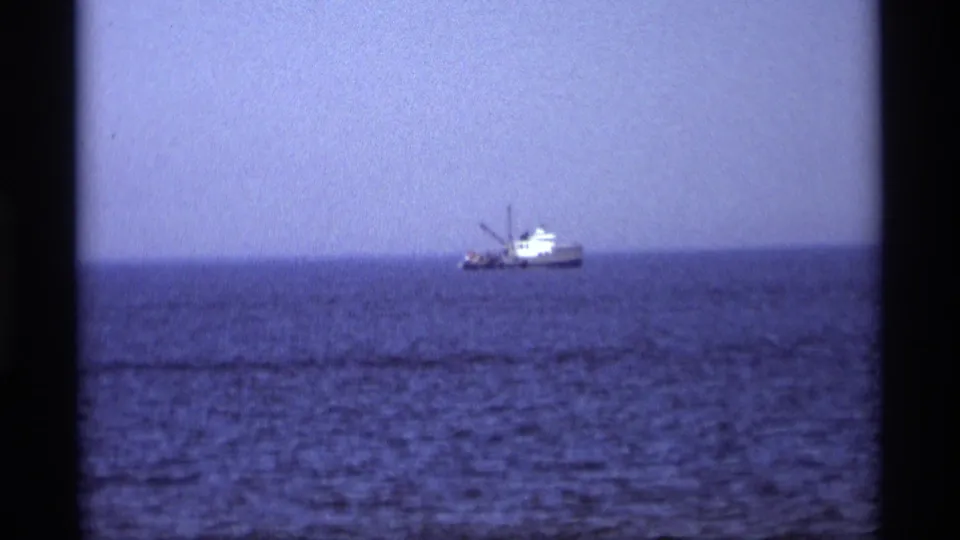 A distant working boat appears on open water in a 1969 Holland, Michigan home-movie shot.