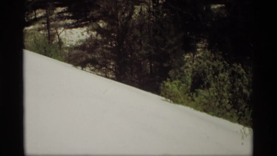 1969 Holland, Michigan 8mm frame with a broad snow bank, shrubs, and trees along the ridge.