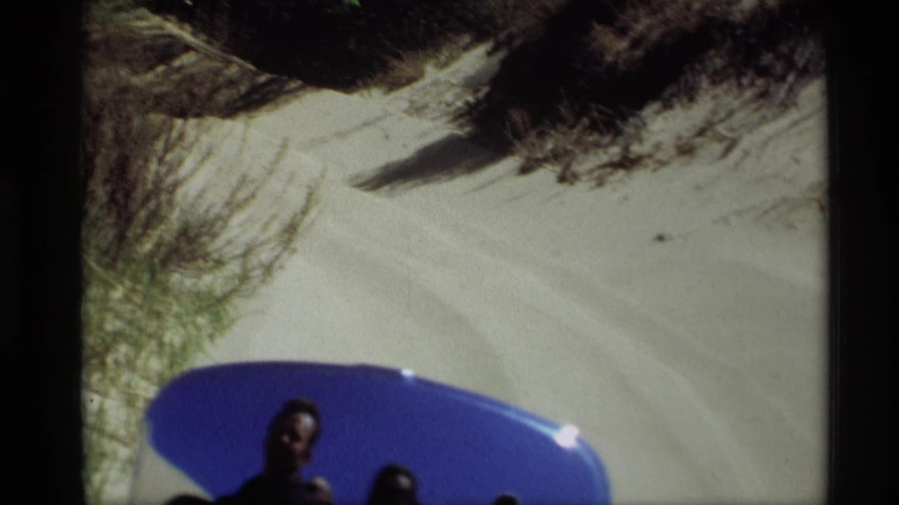 Blue foreground object below a sandy slope, with partial people visible near the bottom edge.