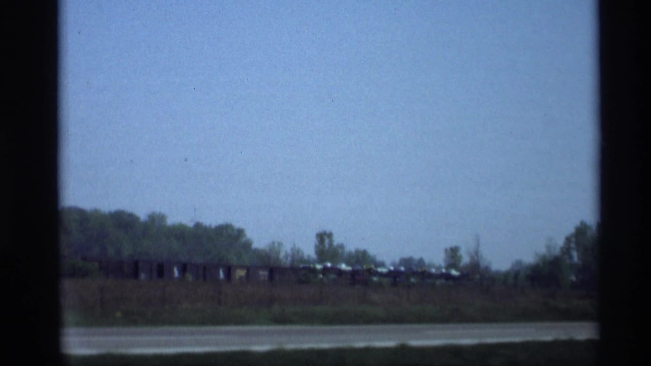 Distant rail or vehicle line beyond a road or water edge.